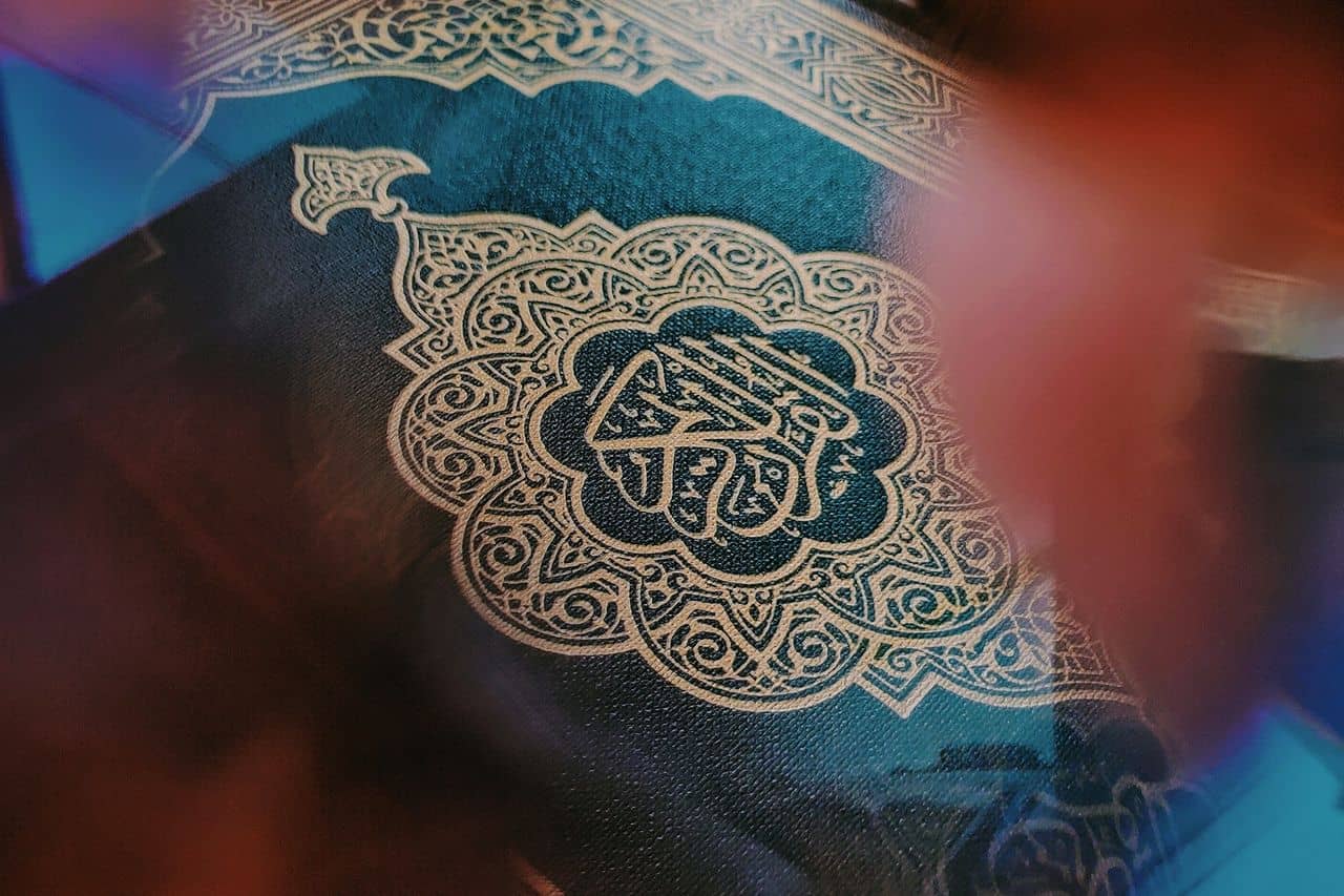 A dark green Quran cover with intricate gold calligraphy and patterns